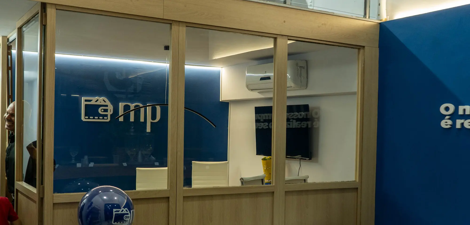 Interior da loja da MP Consórcios, com a marca aplicada na vidraça das salas de atendimento